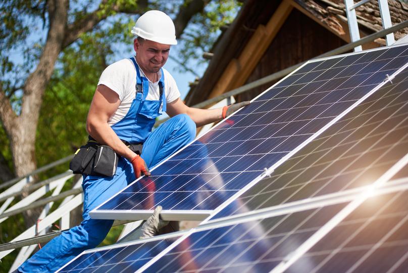 Technician inspecting solar panels on a residential roof in UK